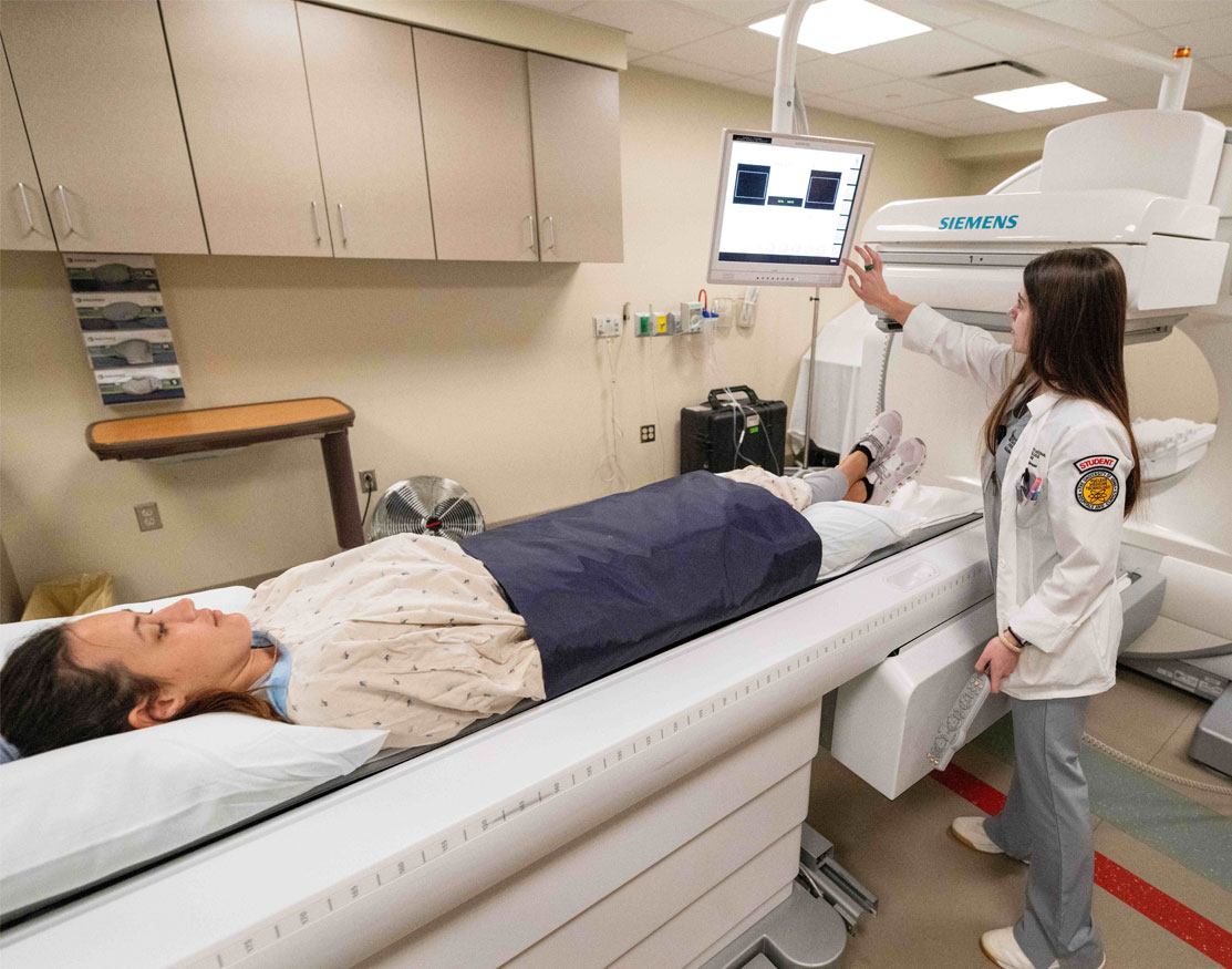 Student performing a CT scan on another student