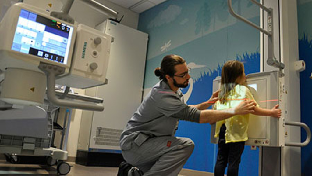Technologist positioning pediatric patient for a chest x-ray