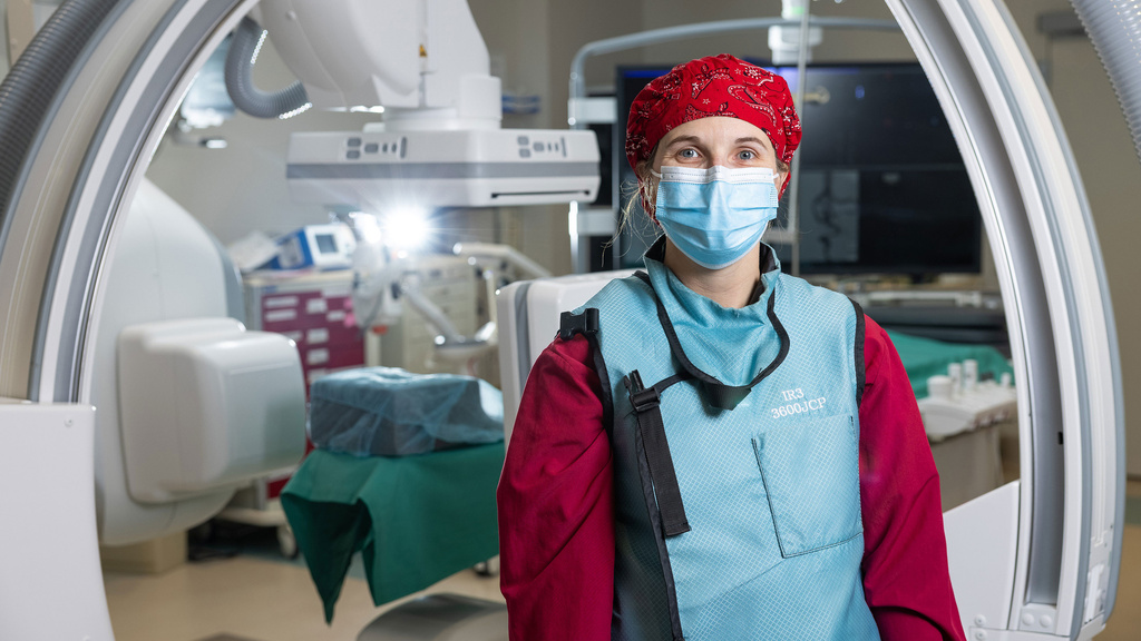 Cardiovascular tech stands in front of a surgical bed 