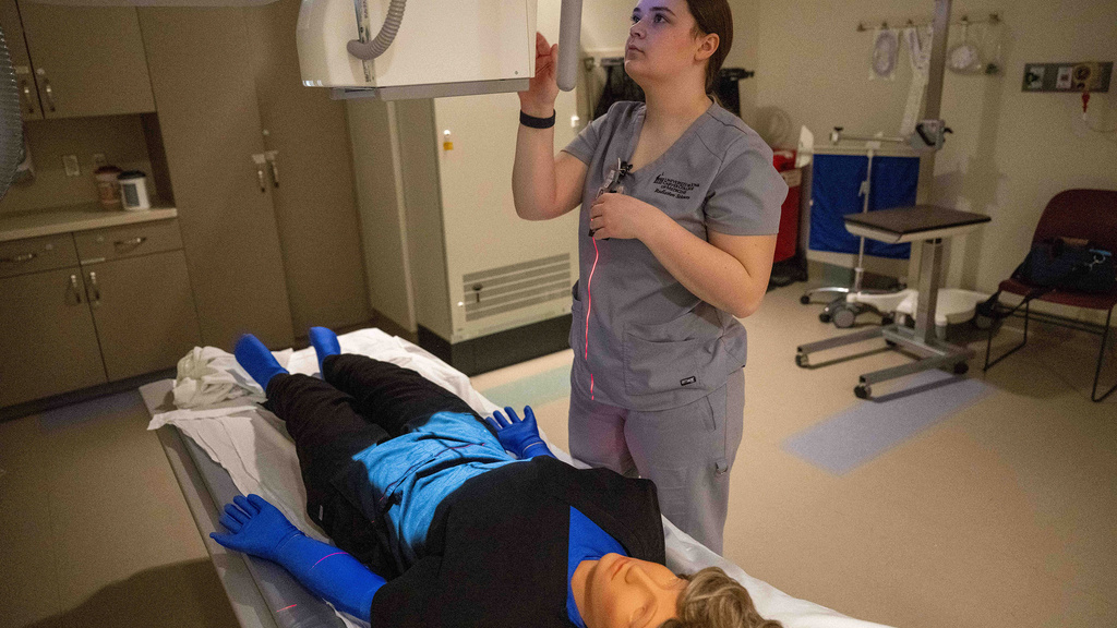 Rad tech student positions dummy on a scanning bed
