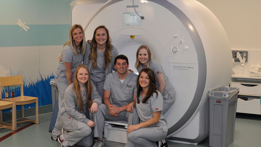Rad tech students pose in front on MRI machine